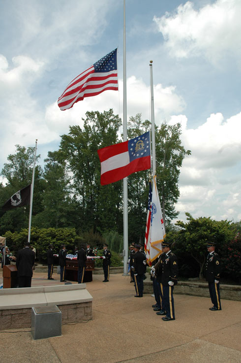 Soldiers lined up by an American and Georgian Flag