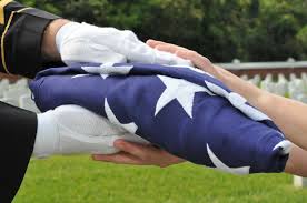 Soldier handing folded flag to family member